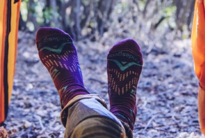 Una persona que lleva calcetines técnicos de montaña Lorpen tiene los pies metidos dentro de una tienda de campaña.