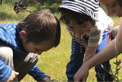 Una madre y un niño están plantando un árbol en un campo.