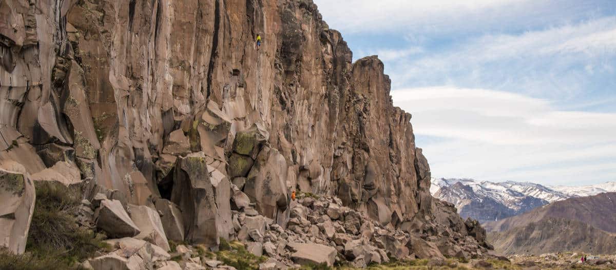 Un hombre está ascendiendo una ruta por la ladera rocosa de una montaña.