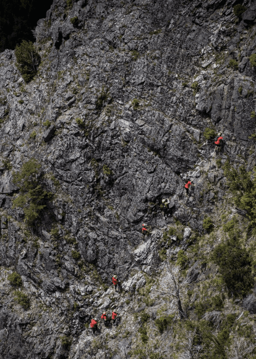 Descripción: Un grupo de personas están escalando una montaña rocosa.