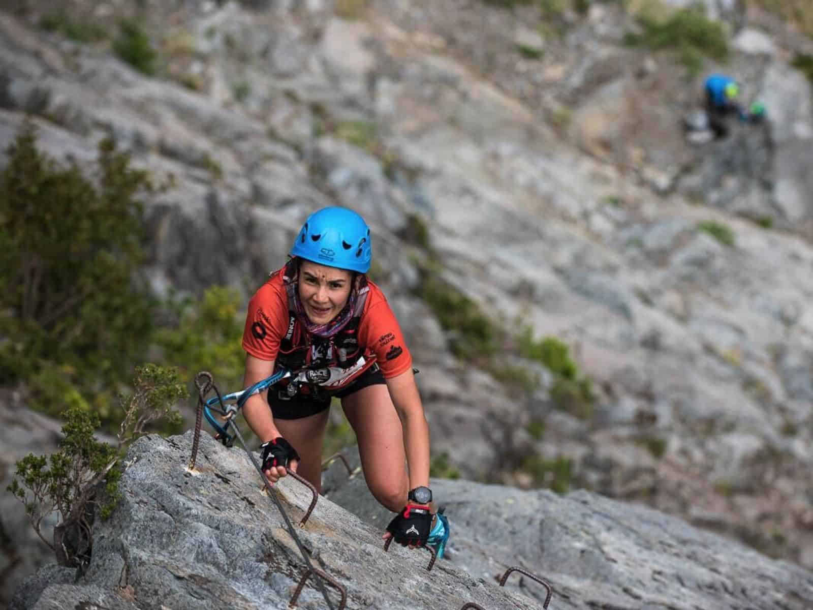 Descripción: Una mujer está escalando una montaña rocosa.
