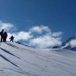 Un grupo de esquiadores disfrutando de la impresionante vista desde la cima de una montaña cubierta de nieve.