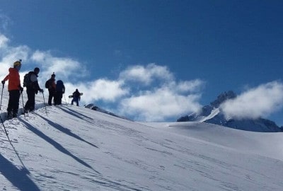 Un grupo de esquiadores disfrutando de la impresionante vista desde la cima de una montaña cubierta de nieve.