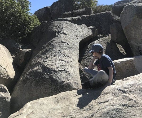 Un niño está sentado encima de una gran roca en el norte.