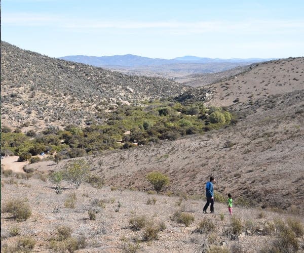 Un hombre y un niño caminando por un sendero en el desierto, en dirección Norte.