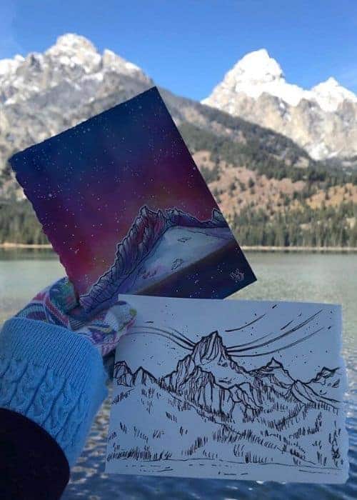 Vicki Speck sosteniendo un dibujo de una montaña y un lago.