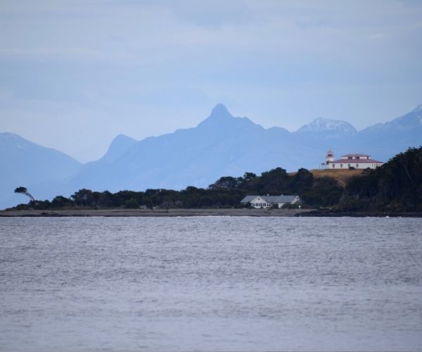 Una pequeña isla en la Patagonia con montañas al fondo.