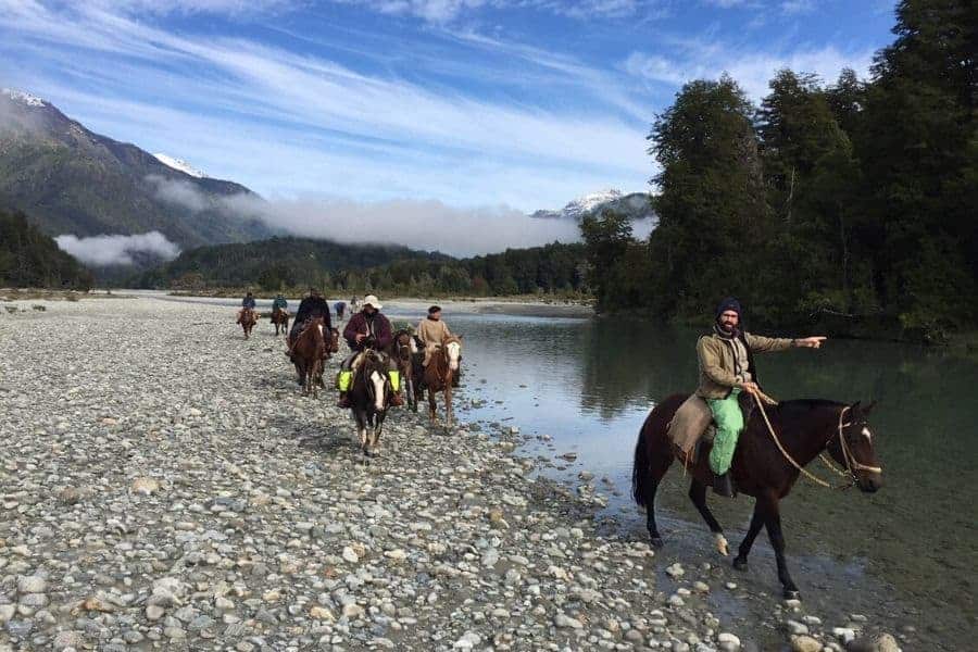 Una cabalgata de gente a caballo a lo largo de un río.