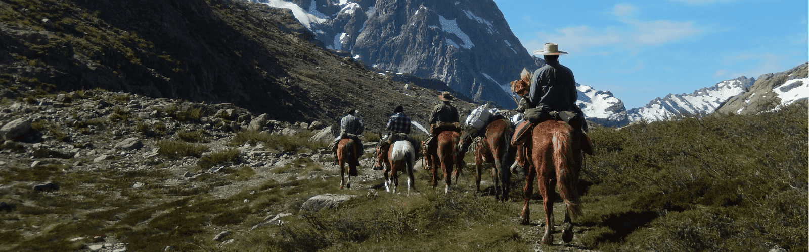 Un grupo de personas participando en una cabalgata en una zona montañosa.