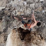 Benja Ayala está trepando a una roca en una cueva.