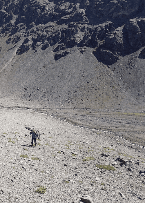 Un hombre esquiando por una zona rocosa en las montañas.