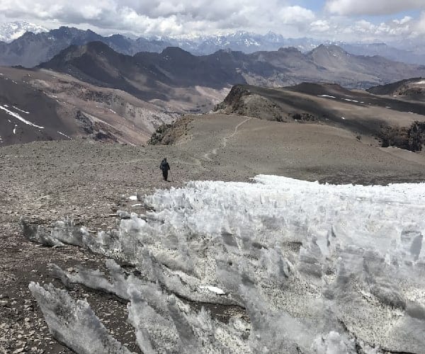 Un hombre camina por una montaña central cubierta de cristales de hielo.
