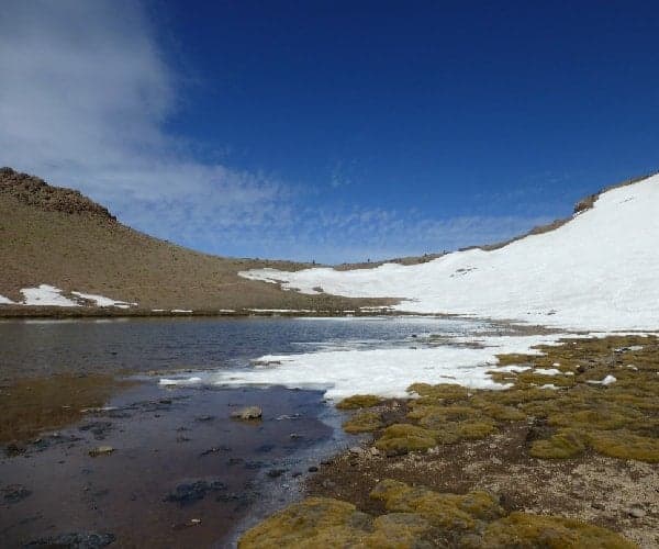 Un lago central en las montañas con nieve en el suelo.