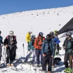 Un grupo de esquiadores alpinos posando frente a una tienda de campaña.