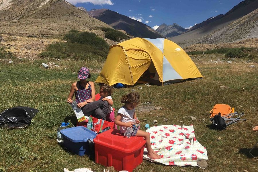 Un grupo de niños sentados alrededor de una tienda de campaña en las montañas durante un viaje de acampada.