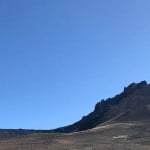 Descripción: Cerro Campanario, una montaña que se eleva en medio de un vasto campo con un cielo azul fascinante.