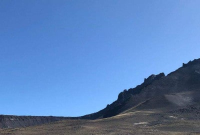 Descripción: Cerro Campanario, una montaña que se eleva en medio de un vasto campo con un cielo azul fascinante.