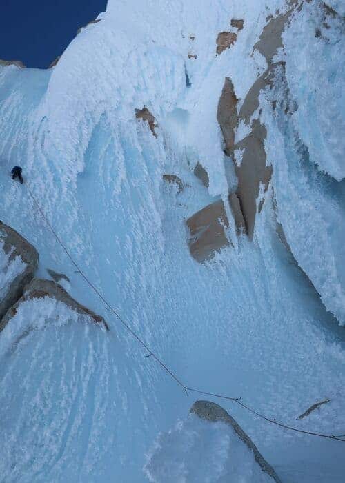 Un escalador escala una torre cubierta de nieve.
