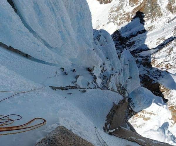 Un escalador está escalando una torre en un acantilado nevado.