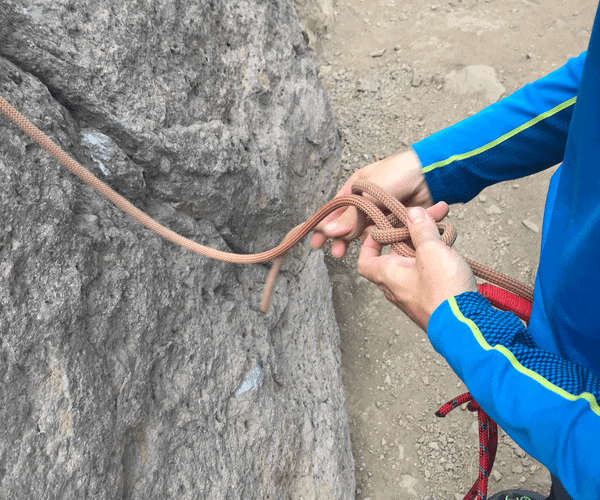 Una persona en Santiago atando una cuerda a una roca para su aventura de escalada.