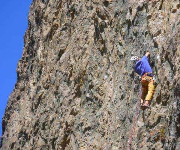 Descripción: Un escalador está escalando una empinada pared de roca en Santiago.