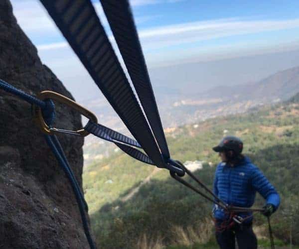 Un hombre está escalando una montaña con una cuerda.