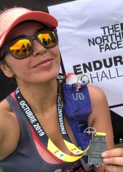 Una mujer mostrando triunfalmente una medalla por completar el desafiante North Face Endurance Challenge.