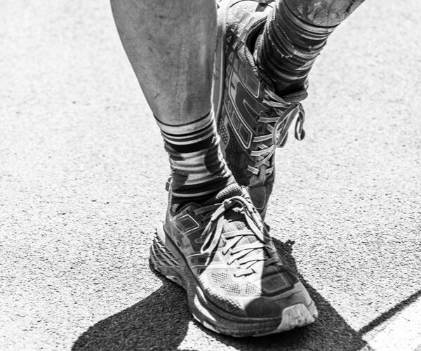 Una fotografía en blanco y negro de los pies de una persona caminando por un sendero.