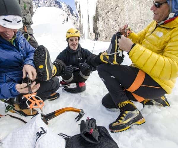 Un grupo de personas sentadas en una montaña nevada, disfrutando de la impresionante vista mientras beben bebidas calientes de sus acogedores termos Anker.