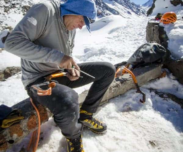 Un hombre está usando un anker para trabajar con una cuerda en la nieve.