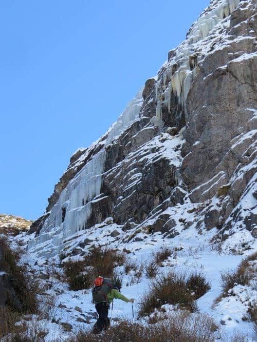 Un hombre escalando una montaña nevada con hielos.
