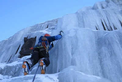 Descripción: Un escalador de hielo subiendo por una gran pared de hielo.