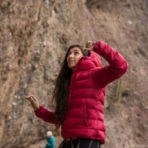 Una mujer con una chaqueta roja parada frente a un acantilado.