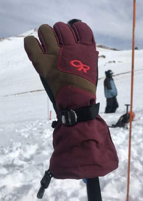Un par de guantes de esquí encima de un bastón de esquí.