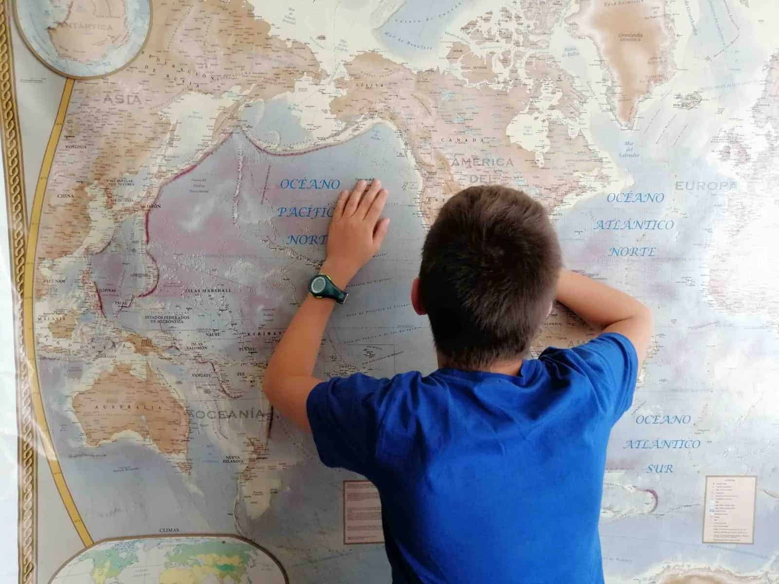 Un niño de familia mirando un mapa mundial en una pared.