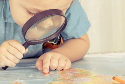 Un niño explorando un mapa con una lupa en compañía de su familia.