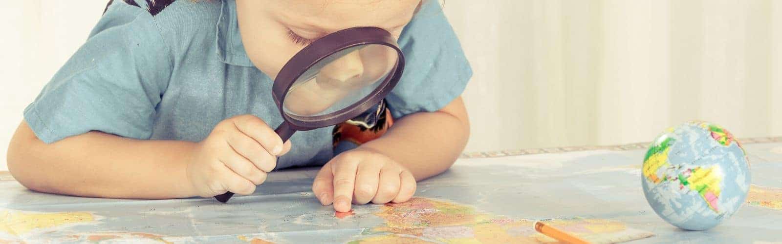 Un niño explorando un mapa con una lupa en compañía de su familia.