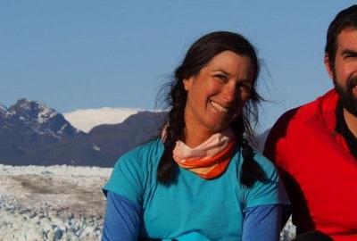 Dos personas paradas frente a un glaciar
