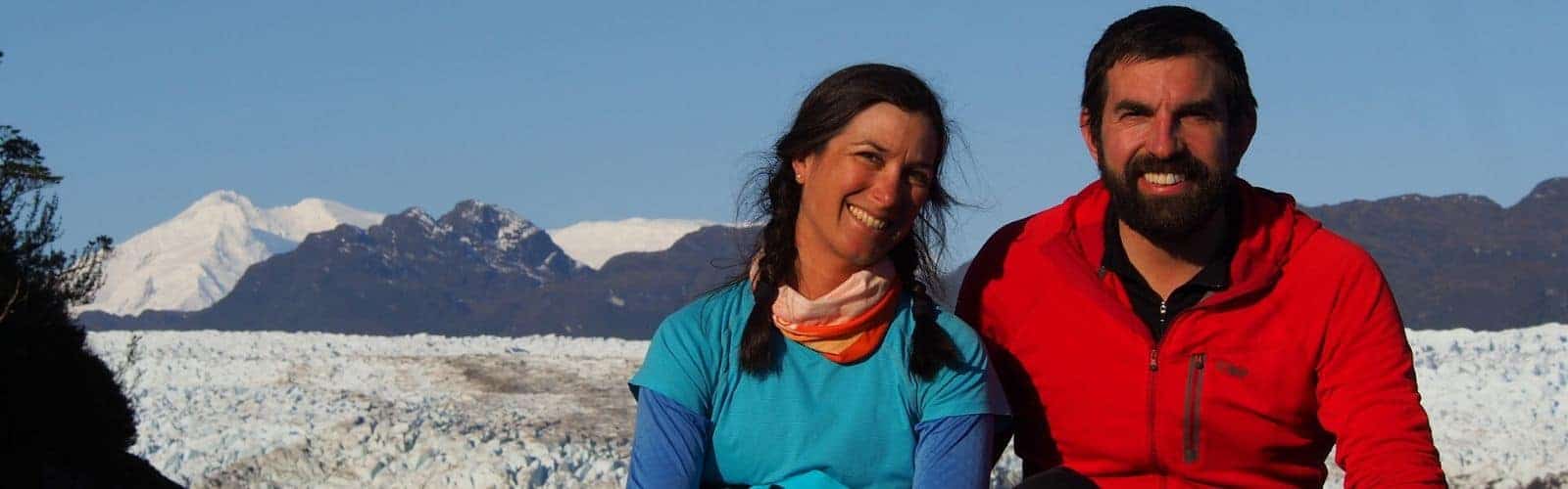 Dos personas paradas frente a un glaciar