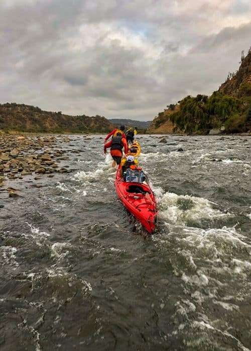 Un grupo de personas acampan en kayak río abajo.