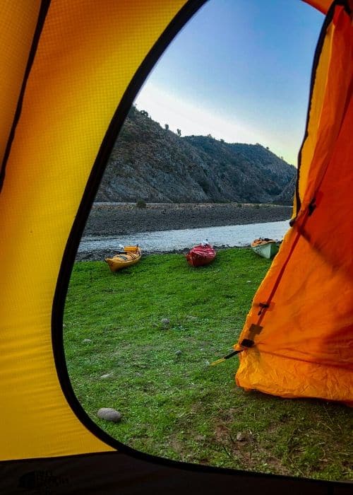 Una tienda de campaña con vista panorámica de un río y alquiler de kayaks opcionales.