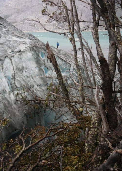 Paula López parada sobre un glaciar extremo cerca de un cuerpo de agua.