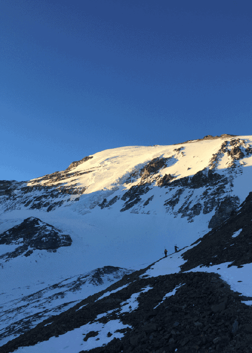 Un grupo de personas escalando una montaña nevada, soportando el desafiante terreno y abrazando la intimidante pero impresionante belleza del plomo.