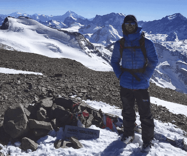 Un hombre parado en la cima de una montaña nevada.