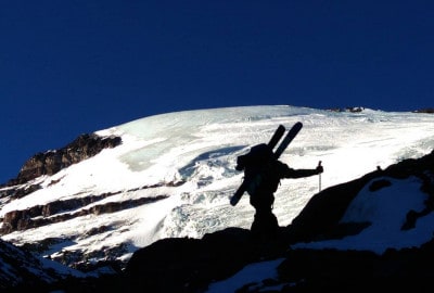 Una persona subiendo una montaña nevada con esquís.