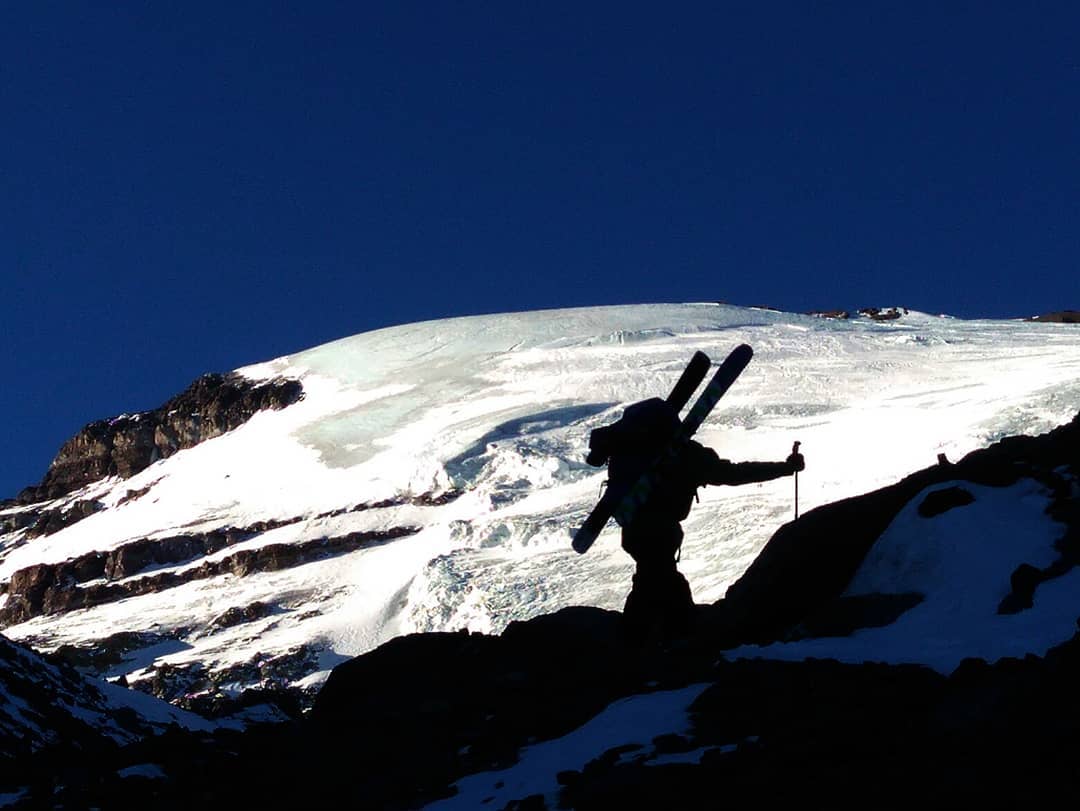 Una persona subiendo una montaña nevada con esquís.