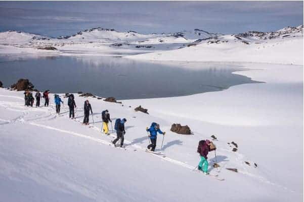 Un grupo de esquiadores rando descendiendo una montaña cubierta de nieve.