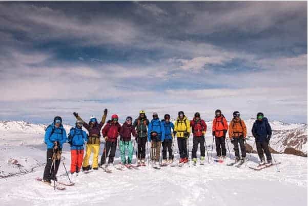 Un grupo de esquiadores rando parados en la cima de una montaña.