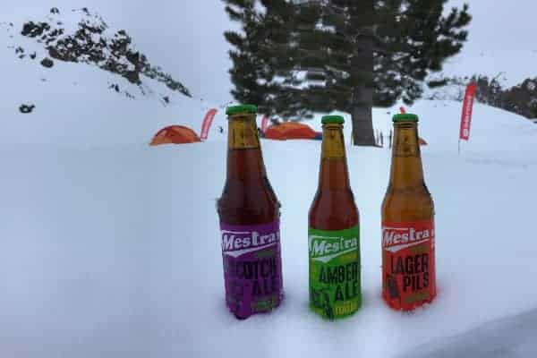 Tres botellas de cerveza en la nieve, con un transeúnte al azar.