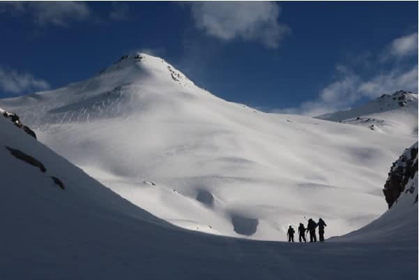 Un grupo de gente rando caminando por una montaña cubierta de nieve.